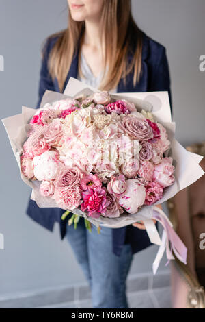 Rosa Pfingstrosen und Hortensien. Schönen Blumenstrauß aus gemischten Blumen in der Frau die Hand. Blumen Shop Konzept. Schönen frischen Blumenstrauß. Blumen Lieferung. Rot und Stockfoto