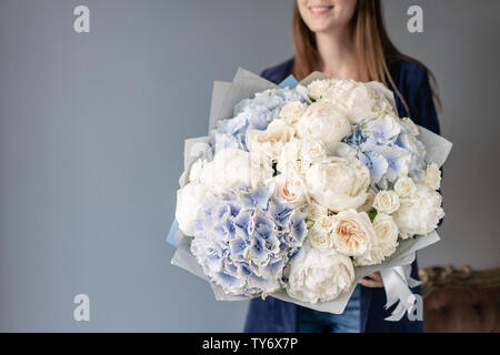 Weiße Pfingstrosen und Blaue Hortensie. Schönen Blumenstrauß aus gemischten Blumen in der Frau die Hand. Blumen Shop Konzept. Schönen frischen Blumenstrauß. Blumen Lieferung Stockfoto