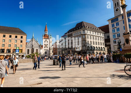 Touristen und Einheimische Flanieren auf dem Marienplatz, der Stadtplatz. Auf dem Hintergrund der Altes Rathaus und der Heiliggeistkirche (Kirche der Heiligen Geist) Stockfoto