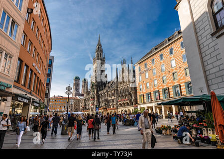 Touristen wandern auf dem Marienplatz der Stadtplatz von München. Im Hintergrund das Neue Rathaus (Neue Rathaus) und die Kathedrale. Bayern, Deutschland Stockfoto