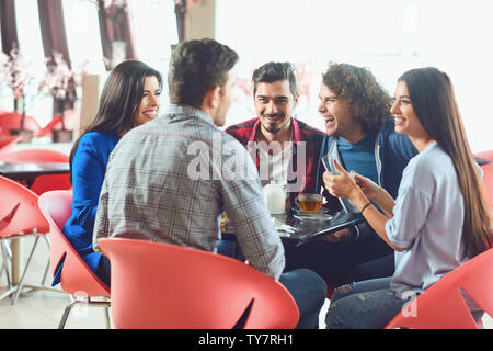 Lustige Freunde lachen an einem Tisch in einem Cafe sitzen. Das Treffen mit Freunden in der Freizeit. Stockfoto