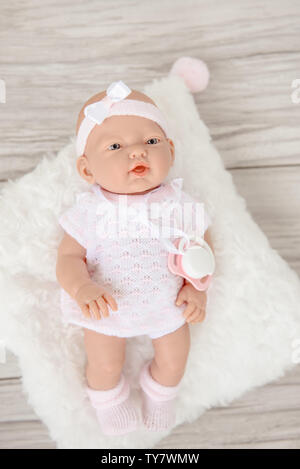 Baby Doll in weißen hellen Kleidung auf beigen Hintergrund isoliert. Stockfoto