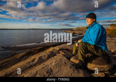 Outdoor Fotograf Øyvind Martinsen mit seinem Kajak in den See Vansjø, Østfold, Norwegen. Vansjø ist ein Teil des Wassers, das System namens Morsavassdraget. Stockfoto