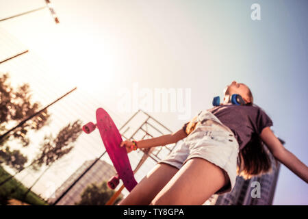 Strahlende langhaarige Teenager ihre persönliche skateboard Holding Stockfoto