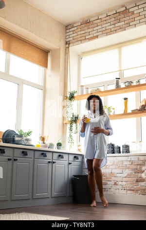 Lächelnd schwangere Frau ihren Bauch berühren in der Küche. Stockfoto