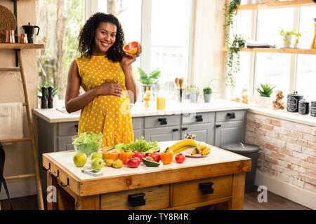 Lächelnd werdende Mutter, die eine Hälfte der Grapefruit. Stockfoto