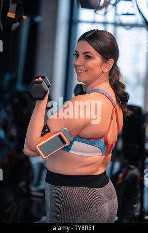 Übergewichtige Frau Gefühl positiv, während Sie im Fitnessraum arbeiten Stockfoto