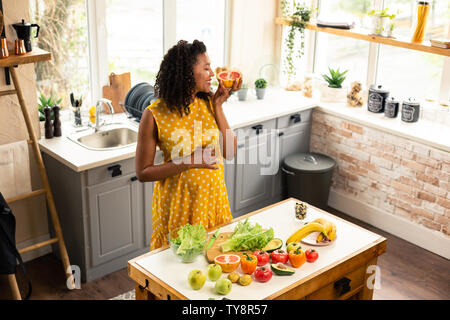 Gerne schwangere Frau riechen eine Grapefruit Hälfte. Stockfoto