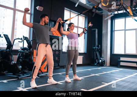 Sportlich attraktiv Fitness Trainer zeigt Frau Übungen Stockfoto