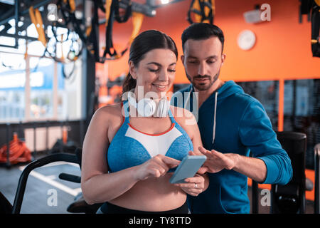 Dunkelhaarige Frau, die Ihre alten Fotos zeigen zu ihrem Trainer Stockfoto