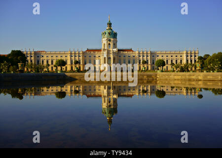 Schloss Charlottenburg, dem größten Palast in Berlin, Deutschland. Durch die frühe Morgensonne im Sommer Sonnenbeschienenen mit schönen Reflexionen in einen Brunnen. Stockfoto