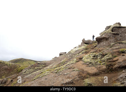 Ein Mann stand auf einem felsigen Hang und mit Blick auf den Horizont Stockfoto