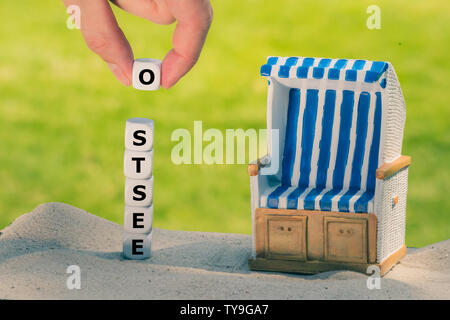 Würfel Form das deutsche Wort "Ostsee" ("Ostsee" in Englisch) Neben einem Strandkorb. Stockfoto