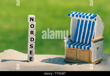 Würfel Form das deutsche Wort "Nordsee" ("Nordsee" in Englisch) Neben einem Strandkorb. Stockfoto