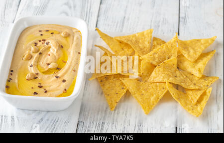 Schüssel mit Hummus mit Tortilla Chips auf dem hölzernen Tisch Stockfoto