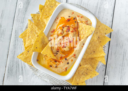 Schüssel mit Hummus mit Tortilla Chips auf dem hölzernen Tisch Stockfoto