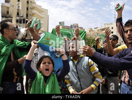 Anhänger der Libyian leader Muammar Gaddafi halten Sie ein Bild der libysche Führer, wie sie Parolen während einer pro Gesang - Regierung Rallye in Tripolis am 19. April 2011. UPI/Ahmad gegangen. Stockfoto