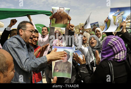 Anhänger der Libyian leader Muammar Gaddafi halten Sie ein Bild der libysche Führer, wie sie Parolen während einer pro Gesang - Regierung Rallye in Tripolis am 19. April 2011. UPI/Ahmad gegangen. Stockfoto