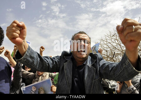 Anhänger der Libyian leader Muammar Gaddafi halten Sie ein Bild der libysche Führer, wie sie Parolen während einer pro Gesang - Regierung Rallye in Tripolis am 19. April 2011. UPI/Ahmad gegangen. Stockfoto