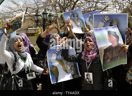 Anhänger der Libyian leader Muammar Gaddafi halten Sie ein Bild der libysche Führer, wie sie Parolen während einer pro Gesang - Regierung Rallye in Tripolis am 19. April 2011. UPI/Ahmad gegangen. Stockfoto