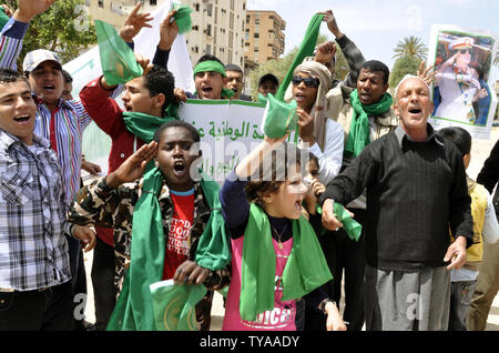 Anhänger der Libyian leader Muammar Gaddafi halten Sie ein Bild der libysche Führer, wie sie Parolen während einer pro Gesang - Regierung Rallye in Tripolis am 19. April 2011. UPI/Ahmad gegangen. Stockfoto