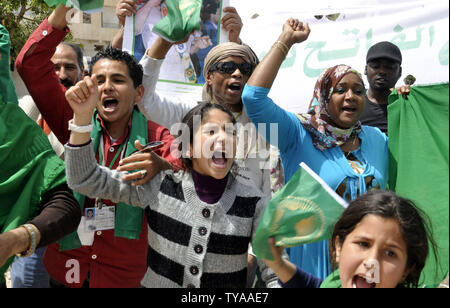 Anhänger der Libyian leader Muammar Gaddafi halten Sie ein Bild der libysche Führer, wie sie Parolen während einer pro Gesang - Regierung Rallye in Tripolis am 19. April 2011. UPI/Ahmad gegangen. Stockfoto