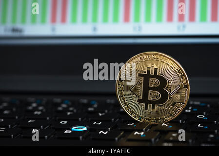 Golden bitcoin auf Laptop Tastatur mit Grafik im Hintergrund Stockfoto