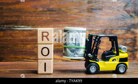 Holzblöcke mit dem Wort ROI und Geld mit einem Gabelstapler. Verhältnis zwischen Gewinn und Investition, die aus einer Investition von Ressourcen Stockfoto
