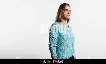 Seitenansicht einer Frau in der kammgarn oben stehend gegen weißen Hintergrund. Frau mit kurzen braunen Haare weg. Stockfoto