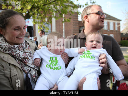 Eltern halten ihre Kinder in Kleidung mit der Konservativen Partei David Cameron's Campaign Slogans, wie sie für seine Ankunft am Palmer College am 24. April in Essex, England 2010 warten. UPI/Hugo Philpott Stockfoto