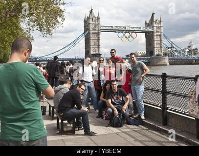 Spanische Touristen nehmen ein Gruppenbild mit der Tower Bridge mit der Olympischen Ringe am Ufer der Themse in London am 21. Juli 2012 geschmückt. Die letzten Vorbereitungen werden mit Eröffnungsfeier für die Olympischen Spiele 2012 sechs Tage entfernt. UPI/Terry Schmitt Stockfoto