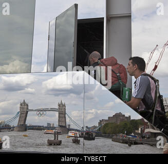 Mitarbeiter geben Sie einen temporären Studio für das französische Fernsehen bis zur Olympiade am Ufer der Themse in London am 21. Juli 2012. Die Tower Bridge geschmückt mit der Olympischen Ringe ist in der Glasfassade wider. UPI/Terry Schmitt Stockfoto