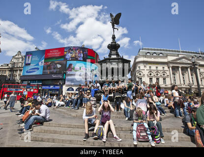 Touristen sitzen in Piccadilly Circus in London am 22. Juli 2012. Fünf Tage bis zur Eröffnung der Olympischen Spiele 2012. UPI/Terry Schmitt Stockfoto