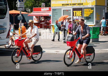 Berlin, Deutschland - Juni, 2019: Touristen Reiten e-Bike Sharing Fahrräder, Springen von UBER auf der Straße in Berlin, Deutschland Stockfoto