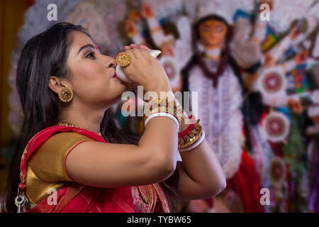 "Porträt einer wunderschönen Bengali Frau blasen Muschel an Durga Puja' Stockfoto