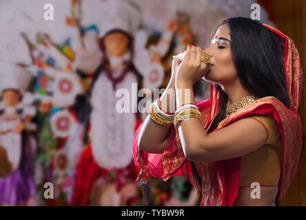 Porträt einer wunderschönen Bengali Frau blasen Muschel an Durga Puja Stockfoto