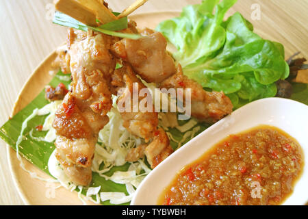 Closeup gegrilltes Hähnchen mit pikanter Sauce und grünem Salat serviert auf Holzplatte Stockfoto