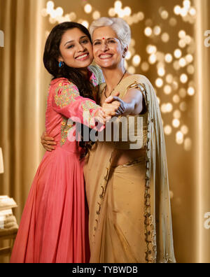 Mutter und Tochter, die traditionelle Kleidung, während glücklich zusammen posieren Interaktion auf Diwali Festival umarmen Stockfoto