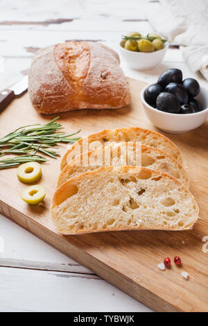Italienische ciabatta Brot mit Oliven und Rosmarin auf einem Holzbrett Stockfoto