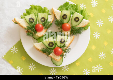 Die Kinder essen, lustige Sandwiches in Form von Tieren. Kindermenü mit grünem Hintergrund Stockfoto