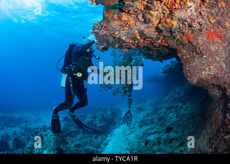 Taucher (MR) Schnitt ein Cargo Net weg vom Riff um Moku Iki Inselchen aus der Northshore von Oahu, Hawaii. Wie kann dies falle und marine Leben töten. Stockfoto