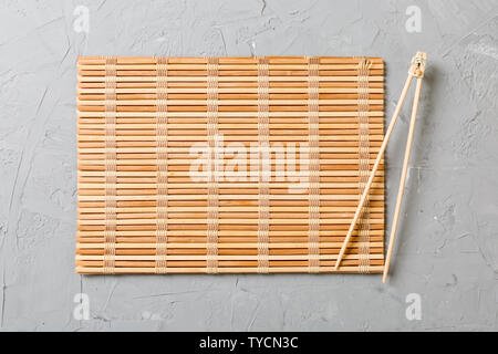 Zwei sushi Ausbildung Sticks mit leeren Bambus matte oder Holzplatte auf Stein Hintergrund Ansicht von oben mit der Kopie Stace. Stockfoto