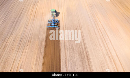 Traktor pflügt das Feld, Ansicht von oben. Der landwirtschaftliche Bereich ist für die Anpflanzung von Gemüse zubereitet. Traktor arbeiten in der Landwirtschaft. Stockfoto