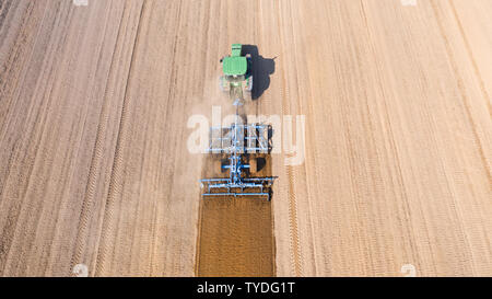 Traktor pflügt das Feld, Ansicht von oben. Der landwirtschaftliche Bereich ist für die Anpflanzung von Gemüse zubereitet. Traktor arbeiten in der Landwirtschaft. Stockfoto