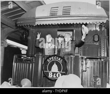 Foto von Präsident Truman schwenkte seinen Hut und Winston Churchill Blinken seiner berühmten V für Sieg Zeichen aus der hinteren Plattform eines speziellen Baltimore & Ohio Zug (offenbar auf dem Weg in Fulton, Missouri für Churchills Eisernen Vorhang Rede), als Präsident der militärischen Adjutanten, allgemeine Harry Vaughan, schaut an. Stockfoto