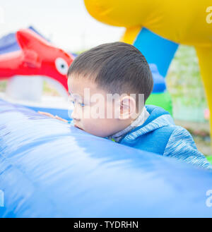 Foto eines 4-jährigen Jungen spielen in einem Vergnügungspark voll von grünen Pflanzen und bunten Windmühlen Stockfoto