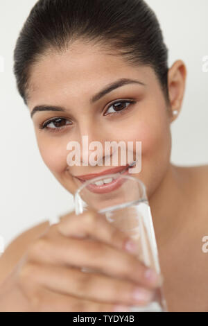 Porträt einer indischen jungen Frau trinkt ein Glas Wasser Stockfoto
