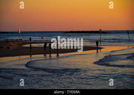 Silhouette von Menschen am Strand bei Sonnenuntergang. Am Strand von Tel Aviv, Israel im März fotografiert. Stockfoto