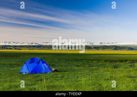 Im Sommer, ein Zelt auf dem Bayinbrook Prairie, und die schneebedeckten Berge in der Ferne sind von der Sonne beschienen Stockfoto