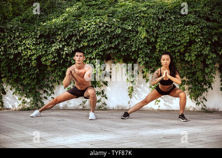 Eine muskulöse Athleten, Training im Park. Gymnastik, Training, Fitness Workout Flexibilität. Sommer Stadt im sonnigen Tag auf Hintergrund Feld. Aktiven und gesunden Lebensstil, Jugend, Bodybuilding. Stockfoto